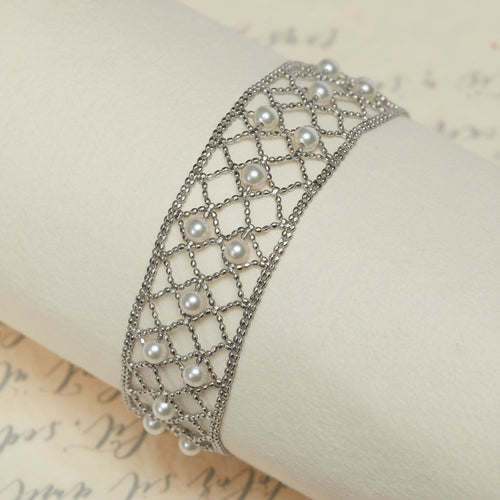 BoxUnboxed 18k yellow gold lace lattice bracelet with Akoya pearls. Features a flexible, woven gold design with small, round pearls.