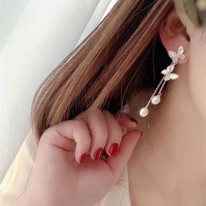 BoxUnboxed gold-plated brass butterfly tassel earrings with freshwater pearls and iridescent shell wings.