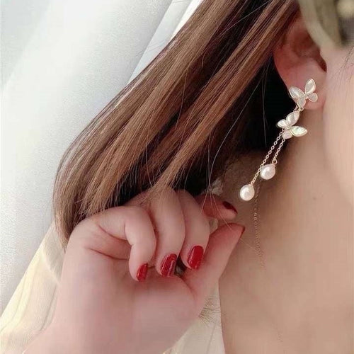 BoxUnboxed gold-plated brass butterfly tassel earrings with freshwater pearls and iridescent shell wings.
