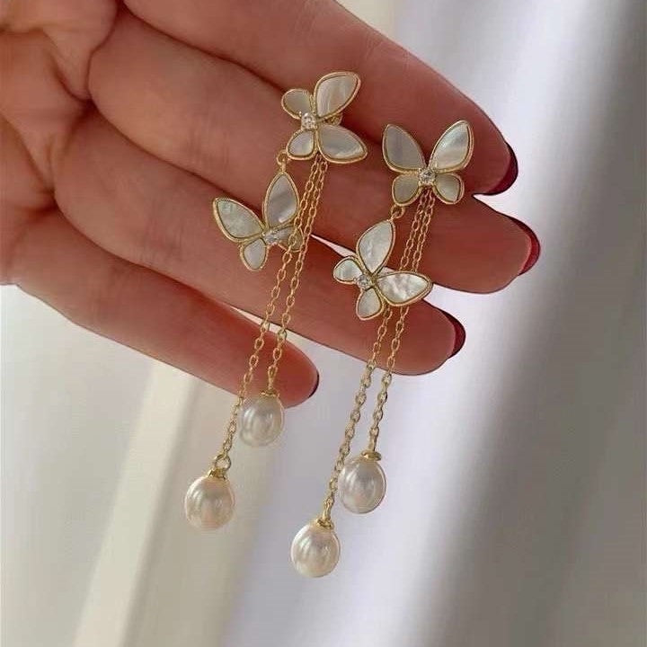 BoxUnboxed gold butterfly tassel earrings with freshwater pearls and iridescent shell wings.