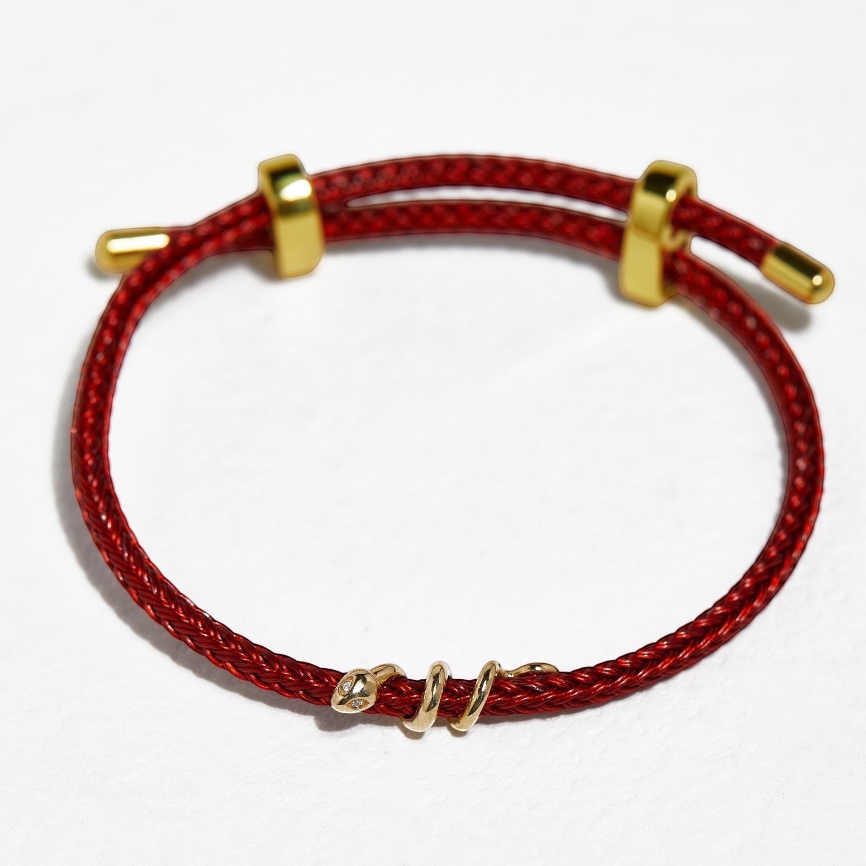 BoxUnboxed 18k solid gold snake bracelet with diamond eyes on a red string cord, adjustable fit.
